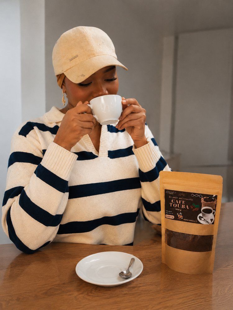 Amyna savoure une tasse de Café Touba, à côté d'un sachet de 500 g